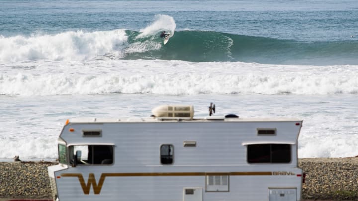 SAN DIEGO, CA – DECEMBER 11: A surfer slashes a large wave crashing while an RV is parked in the foreground on December 11, 2014 in San Diego, California. (Photo by Gabe LHeureux/Getty Images)