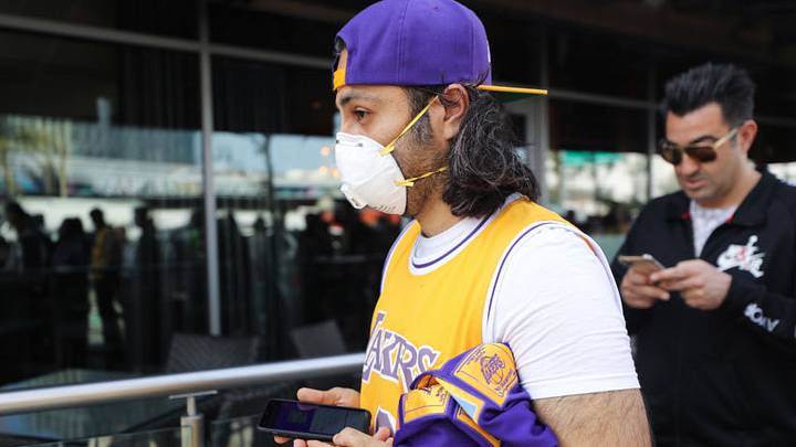 LOS ANGELES, CALIFORNIA - FEBRUARY 24: A fan wears a protective mask as people wait in line to attend the ‘Celebration of Life for Kobe and Gianna Bryant’ memorial service at Staples Center on February 24, 2020 in Los Angeles, California. Los Angeles Lakers NBA star Kobe Bryant, 41, and his 13-year-old daughter Gianna were killed along with seven others in a helicopter crash near Los Angeles on January 26. (Photo by Mario Tama/Getty Images)