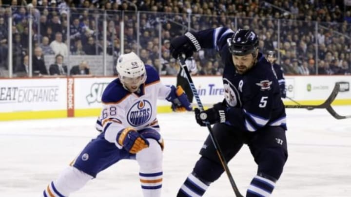 Dec 3, 2014; Winnipeg, Manitoba, CAN; Winnipeg Jets defenceman Mark Stuart (5) battles to control the puck against Edmonton Oilers forward Tyler Pitlick (68) during the first period at MTS Centre. Mandatory Credit: Bruce Fedyck-USA TODAY Sports