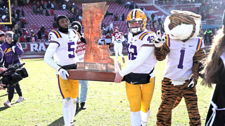 Nov 12, 2022; Fayetteville, Arkansas, USA; LSU Tigers safety Jay Ward and defensive end Lane Blue (42) carry The Boot trophy after the game against the Arkansas Razorbacks at Donald W. Reynolds Razorback Stadium. LSU won 13-10. Mandatory Credit: Nelson Chenault-USA TODAY Sports