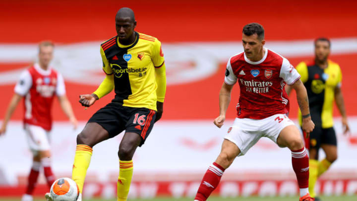 LONDON, ENGLAND - JULY 26: Abdoulaye Doucoure of Watford passe the ball with pressure from Granit Xhaka of Arsenal during the Premier League match between Arsenal FC and Watford FC at Emirates Stadium on July 26, 2020 in London, England. Football Stadiums around Europe remain empty due to the Coronavirus Pandemic as Government social distancing laws prohibit fans inside venues resulting in all fixtures being played behind closed doors. (Photo by Julian Finney/Getty Images)