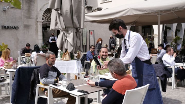TRENTO, ITALY - APRIL 19: The people sitting at the outdoor tables of the restaurants finally eat together happy for the opportunity to meet on April 19, 2021 in Trento, Italy. A week earlier than expected at national level, bars and restaurants will open on Monday 19. The regulation requires compliance with the anti Covid 19 rules, with tables only outside, with a maximum of 4 people for each table, with maximum opening hours from 5:00 to 18:00. (Photo by Alessio Coser/Getty Images)