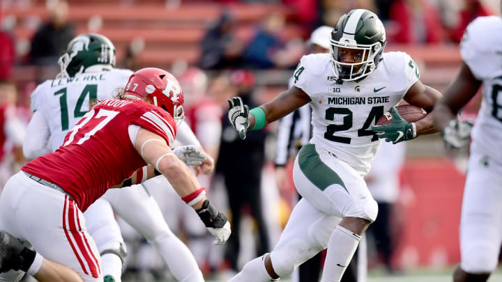 PISCATAWAY, NEW JERSEY – NOVEMBER 23: Elijah Collins #24 of the Michigan State Spartans stiff arms Mike Tverdov #97 of the Rutgers Scarlet Knights during the second half of their game at SHI Stadium on November 23, 2019 in Piscataway, New Jersey. (Photo by Emilee Chinn/Getty Images)