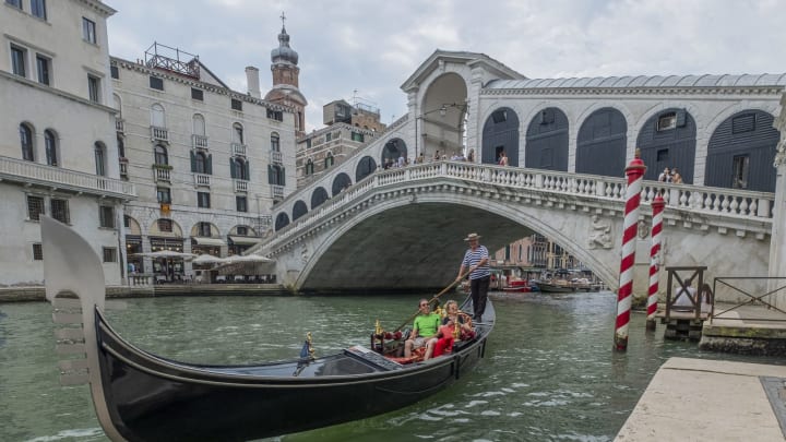 VENICE, ITALY – JULY 22: Gondolier takes tourists near the Rialto Bridge on July 22, 2020 in Venice, Italy. A new rule in Venice will make becoming a gondolier more difficult by asking to prove that you have been working for the last four years on a family Gondola. (Photo by Stefano Mazzola/Awakening/Getty Images)V