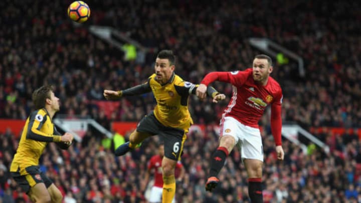 MANCHESTER, ENGLAND – NOVEMBER 19: Laurent Koscielny of Arsenal (C) and Wayne Rooney of Manchester United (R) battle for possession in the air during the Premier League match between Manchester United and Arsenal at Old Trafford on November 19, 2016 in Manchester, England. (Photo by Shaun Botterill/Getty Images)