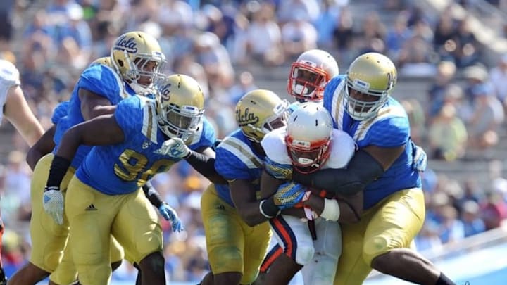 September 5, 2015; Pasadena, CA, USA; Virginia Cavaliers running back Taquan Mizzell (4) is brought down against the UCLA Bruins defense during the second half at the Rose Bowl. Mandatory Credit: Gary A. Vasquez-USA TODAY Sports September 5, 2015; Pasadena, CA, USA; Virginia Cavaliers running back Taquan Mizzell (4) is brought down against the UCLA Bruins defense during the second half at the Rose Bowl. Mandatory Credit: Gary A. Vasquez-USA TODAY Sports