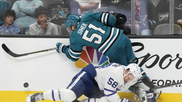 SAN JOSE, CALIFORNIA - OCTOBER 27: Michael Bunting #58 of the Toronto Maple Leafs collides against the boards and Radim Simek #51 of the San Jose Sharks in the third period at SAP Center on October 27, 2022 in San Jose, California. (Photo by Thearon W. Henderson/Getty Images)