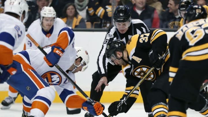 BOSTON, MA - DECEMBER 09: New York Islanders center John Tavares (91) and Boston Bruins center Patrice Bergeron (37) take the face off from linesman Brian Murphy (93) during a game between the Boston Bruins and the New York Islanders on December 9, 2017, at TD Garden in Boston, Massachusetts, The Bruins defeated the Islanders 3-1. (Photo by Fred Kfoury III/Icon Sportswire via Getty Images)