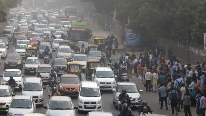 Indian commuters (R) wait for a bus next to heavy traffic on a smoggy morning in New Delhi on November 14, 2017.Doctors declared a public health emergency in New Delhi when choking smog descended on the capital and elsewhere in northern India, prompting authorities to close schools, ban construction and bar trucks from entering the city. / AFP PHOTO / DOMINIQUE FAGET (Photo credit should read DOMINIQUE FAGET/AFP/Getty Images)