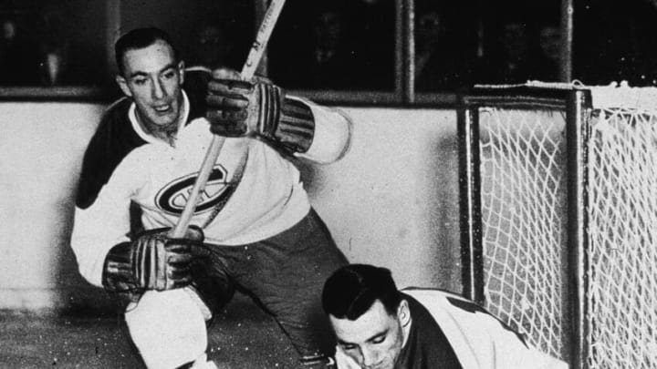 Montreal Canadiens goalkeeper Jacques Plante makes a save as teammate Bud McPherson watches, stick raised, 1954. (Photo by Hulton Archive/Getty Images)