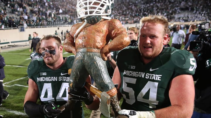 EAST LANSING, MI – OCTOBER 25: Marcus Rush #44 of the Michigan State Spartans and teammate Connor Kruse #54 celebrate a win over the Michigan Wolverines and carry off the Paul Paul Bunyan trophy at Spartan Stadium on October 25 , 2014 in East Lansing, Michigan. The Spartans defeated the Wolverines 35-11 (Photo by Leon Halip/Getty Images)