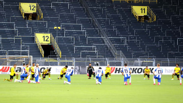 Borussia Dortmund and Hertha BSC players kneel together in solidarity.