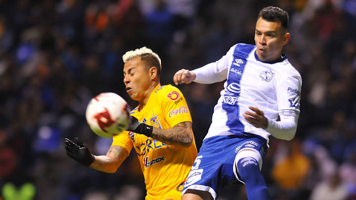 Jugadores de Tigres UANL y Puebla pelean por un balón.