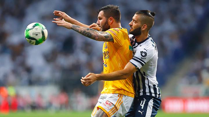 Jugador de Rayados de Monterrey y de Tigres UANL disputan una pelota.