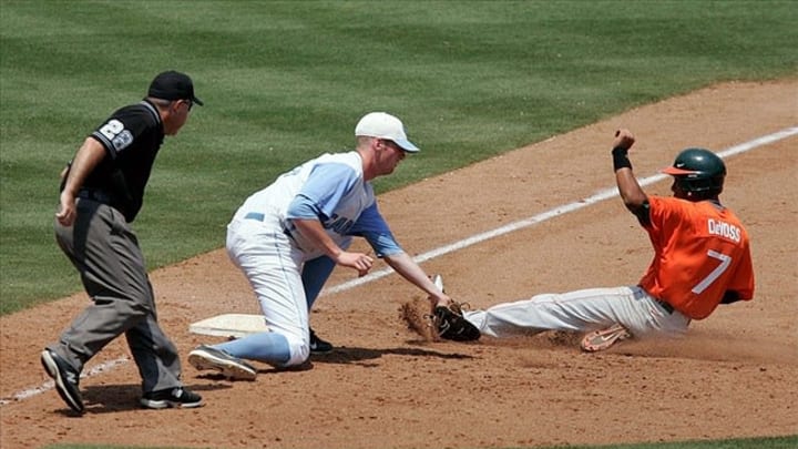 May 26, 2011; Durham, NC, USA; Miami Hurricanes second baseman Zeke DeVoss (7) slides safely into third as North Carolina Tar Heels third baseman Colin Moran (18) misses the tag on the second day of the 2011 ACC baseball tournament at the Durham Bulls Athletic Park. Mandatory Credit: Mark Dolejs-US PRESSWIRE