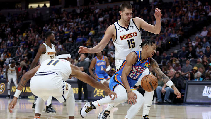 DENVER, COLORADO – OCTOBER 03: Tre Mann #23 of the Oklahoma City Thunder is tripped up driving to the basket against Bruce Brown #11and Nikola Jokic #15 of the Denver Nuggets in the first period during a pre-season game at Ball Arena on October 3, 2022 in Denver, Colorado. (Photo by Matthew Stockman/Getty Images)