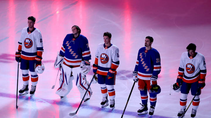 The New York Islanders and the New York Rangers stand together as the Canadian and American national anthems are played before the start of an exhibition game.