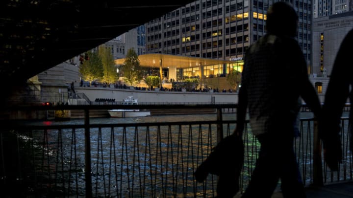 Pedestrians walk on a sidewalk along the Chicago River across from the new Apple Inc. Michigan Avenue store in Chicago, Illinois, U.S., on Friday, Oct. 20, 2017. The building features exterior walls made entirely of glass with four interior columns supporting a 111-by-98 foot carbon-fiber roof, designed to minimize the boundary between the city and the Chicago River. Photographer: Daniel Acker/Bloomberg via Getty Images