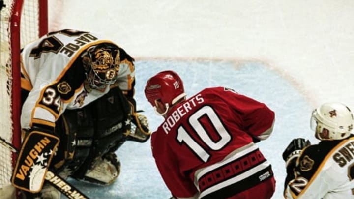 26 Apr 1999: Goalie Byron Dafoe #34 of the Boston Bruins blocks the shot to the goal by Gary Roberts #10 of the Carolina Hurricanes during the Eastern Conference Quarter Finals Game Three at the Fleet Center in Boston, Massachusetts. The Hurricanes defeated the Bruins 2-1.