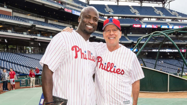 PHILADELPHIA, PA - MAY 15: Co-host for American Ninja Warrior, Akbar Gbaja-Biamila and actor Bruce Willis pose during batting practice prior to Bruce Willis throwing the ceremonial pitch at the Milwaukee Brewers v Philadelphia Phillies game at Citizens Bank Park on May 15, 2019 in Philadelphia, Pennsylvania. (Photo by Gilbert Carrasquillo/Getty Images)