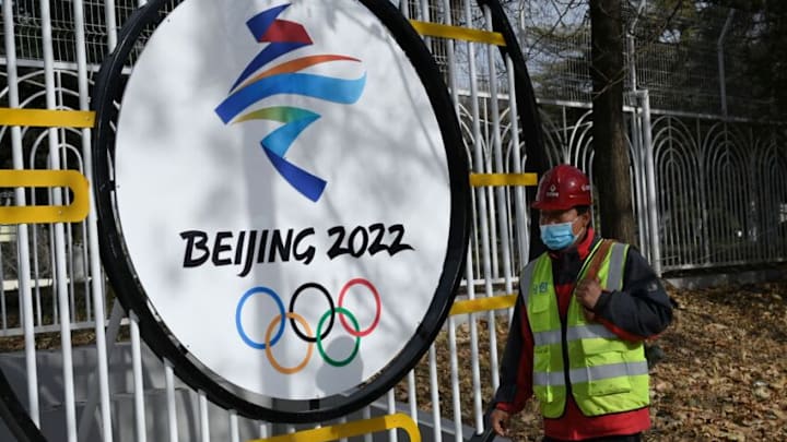 A construction worker walks past the Beijing 2022 Winter Olympic Games logo on a street in Beijing on December 11, 2021. (Photo by JADE GAO / AFP) (Photo by JADE GAO/AFP via Getty Images)