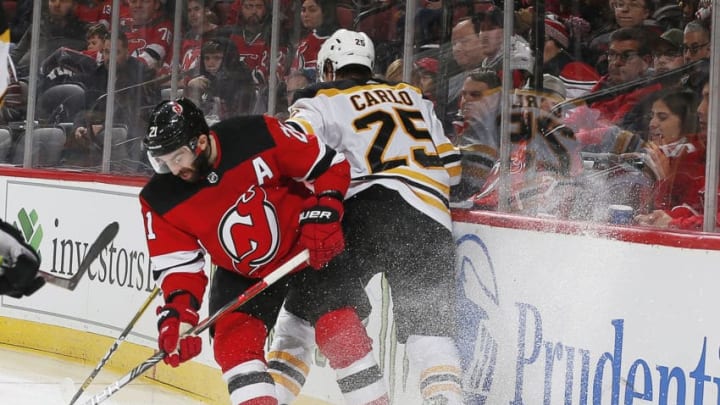 NEWARK, NJ - DECEMBER 31: Kyle Palmieri #21 of the New Jersey Devils and Brandon Carlo #25 of the Boston Bruins battle against the boards during the game at the Prudential Center on December 31, 2019 in Newark, New Jersey. (Photo by Andy Marlin/NHLI via Getty Images)