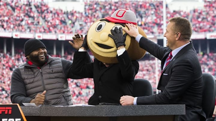 Nov 26, 2016; Columbus, OH, USA; Former Ohio State Buckeyes players Orlando Pace (l) and Kirk Herbstreit (r) laugh as ESPN College Gameday host Lee Corso dons the head of Brutus Buckeye, signifying his pick for the game against the Michigan Wolverines at Ohio Stadium. Ohio State won the game 30-27 in double overtime. Mandatory Credit: Greg Bartram-USA TODAY Sports