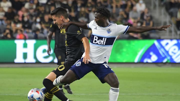 Los Angeles FC midfielder Eduard Atuesta (20) and Vancouver Whitecaps midfielder Janio Bikel (19) battle for the ball in the second half at Banc of California Stadium. Mandatory Credit: Jayne Kamin-Oncea-USA TODAY Sports