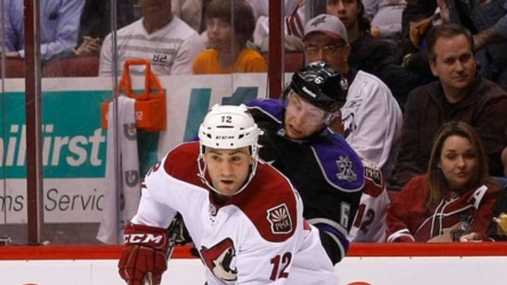 March 12, 2013; Glendale, AZ, USA; Phoenix Coyotes left wing Paul Bissonnette (12) steals the puck from Los Angeles Kings defenseman Jake Muzzin (6) during the second period at Jobing.com Arena. Mandatory Credit: Rick Scuteri-USA TODAY Sports