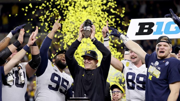 INDIANAPOLIS, INDIANA - DECEMBER 04: Head coach Jim Harbaugh of the Michigan Wolverines celebrates with the trophy after the Michigan Wolverines defeated the Iowa Hawkeyes 42-3 to win the Big Ten Championship game at Lucas Oil Stadium on December 04, 2021 in Indianapolis, Indiana. (Photo by Dylan Buell/Getty Images)
