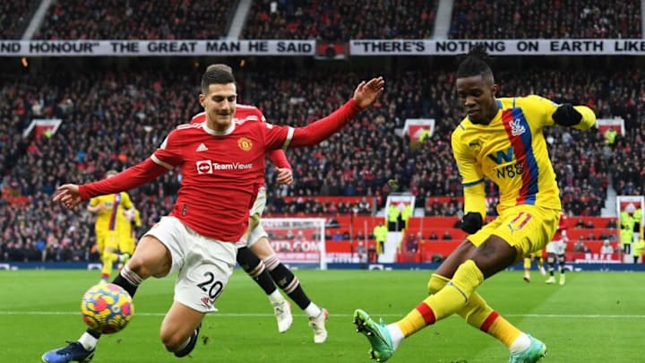 Manchester United's Portuguese defender Diogo Dalot (L) vies with Crystal Palace's Ivorian striker Wilfried Zaha (R) during the English Premier League football match between Manchester United and Crystal Palace at Old Trafford in Manchester, north west England, on December 5, 2021. - RESTRICTED TO EDITORIAL USE. No use with unauthorized audio, video, data, fixture lists, club/league logos or 'live' services. Online in-match use limited to 120 images. An additional 40 images may be used in extra time. No video emulation. Social media in-match use limited to 120 images. An additional 40 images may be used in extra time. No use in betting publications, games or single club/league/player publications. (Photo by Paul ELLIS / AFP) / RESTRICTED TO EDITORIAL USE. No use with unauthorized audio, video, data, fixture lists, club/league logos or 'live' services. Online in-match use limited to 120 images. An additional 40 images may be used in extra time. No video emulation. Social media in-match use limited to 120 images. An additional 40 images may be used in extra time. No use in betting publications, games or single club/league/player publications. / RESTRICTED TO EDITORIAL USE. No use with unauthorized audio, video, data, fixture lists, club/league logos or 'live' services. Online in-match use limited to 120 images. An additional 40 images may be used in extra time. No video emulation. Social media in-match use limited to 120 images. An additional 40 images may be used in extra time. No use in betting publications, games or single club/league/player publications. (Photo by PAUL ELLIS/AFP via Getty Images)