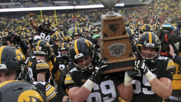 IOWA CITY, IOWA- NOVEMBER 23: Offensive linemen Keegan Render #69 and Ross Reynolds #59 of the Iowa Hawkeyes carry the Heroes Trophy off the field after their match-up against the Nebraska Cornhuskers on November 23, 2018 at Kinnick Stadium, in Iowa City, Iowa. (Photo by Matthew Holst/Getty Images)
