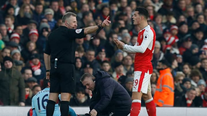 English referee Jonathan Moss (L) gestures to Arsenal's Swiss midfielder Granit Xhaka after he makes a challenge on Burnley's Belgian midfielder Steven Defour during the English Premier League football match between Arsenal and Burnley at the Emirates Stadium in London on January 22, 2017. / AFP / Ian KINGTON / RESTRICTED TO EDITORIAL USE. No use with unauthorized audio, video, data, fixture lists, club/league logos or 'live' services. Online in-match use limited to 75 images, no video emulation. No use in betting, games or single club/league/player publications. / (Photo credit should read IAN KINGTON/AFP/Getty Images)