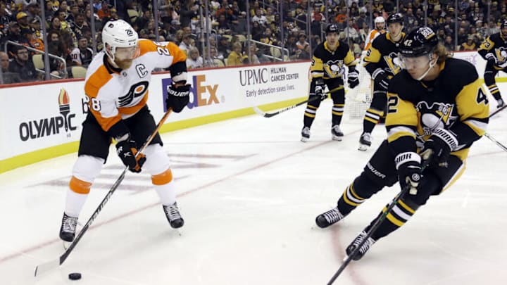 Nov 4, 2021; Pittsburgh, Pennsylvania, USA; Philadelphia Flyers center Claude Giroux (28) moves the puck against Pittsburgh Penguins right wing Kasperi Kapanen (42) during the third period at PPG Paints Arena. Mandatory Credit: Charles LeClaire-USA TODAY Sports