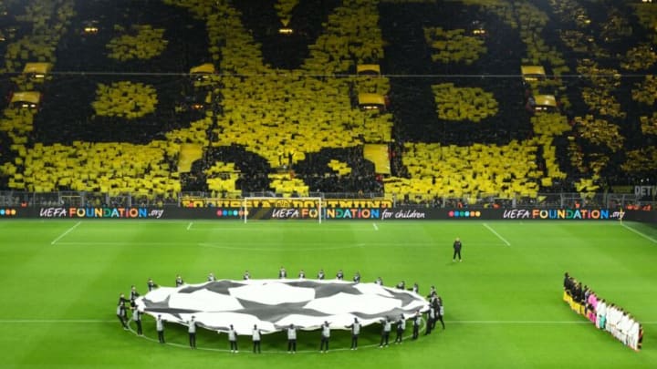 Dortmund fans display their team's logo as the teams line up (R) prior to the UEFA Champions League Last 16, first-leg football match BVB Borussia Dortmund v Paris Saint-Germain (PSG) in Dortmund, western Germany, on February 18, 2020. (Photo by Ina Fassbender / AFP) (Photo by INA FASSBENDER/AFP via Getty Images)