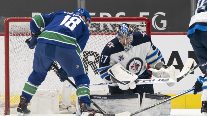Jake Virtanen of the Vancouver Canucks and Connor Hellebuyck of the Winnipeg Jets. (Photo by Rich Lam/Getty Images)