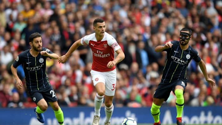 LONDON, ENGLAND - AUGUST 12: Granit Xhaka of Arsenal runs with the ball under pressure from Bernardo Silva of Manchester City and Ilkay Gundogan of Manchester City during the Premier League match between Arsenal FC and Manchester City at Emirates Stadium on August 12, 2018 in London, United Kingdom. (Photo by Shaun Botterill/Getty Images)