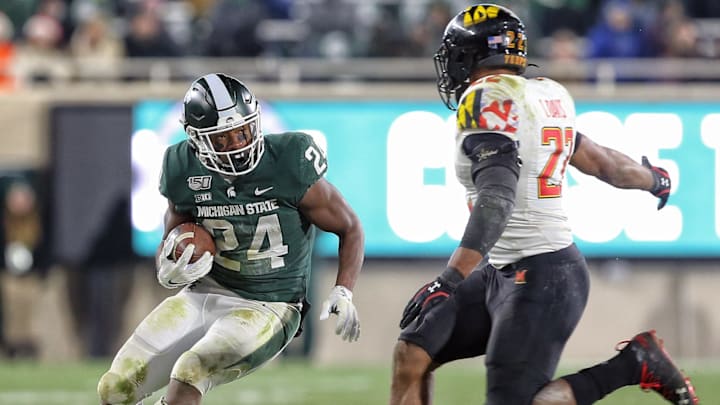 Nov 30, 2019; East Lansing, MI, USA; Michigan State Spartans running back Elijah Collins (24) runs the ball in front of Maryland Terrapins defensive lineman Bryce Brand (27) during the second half a game at Spartan Stadium. Mandatory Credit: Mike Carter-USA TODAY Sports