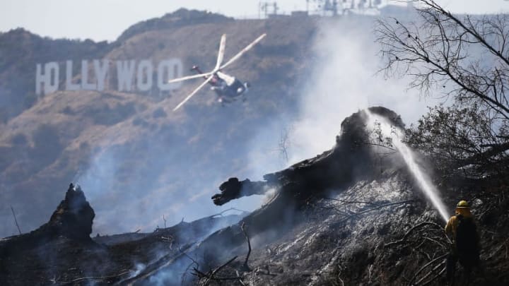 LOS ANGELES, CA - JULY 10: Firefighter personnel, including a helicopter crew, battle the Griffith fire at Griffith Park near the historic Griffith Observatory and the iconic Hollywood sign on July 10, 2018 in Los Angeles, California. Numerous fires have been sparked in Southern California during an ongoing heat wave. (Photo by Mario Tama/Getty Images)