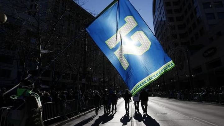 Feb 5, 2014; Seattle, WA, USA; A Seattle Seahawks fan carries a 12th Man flag down 4th Avenue before a Super Bowl championship parade to begin in downtown Seattle. Mandatory Credit: Joe Nicholson-USA TODAY Sports