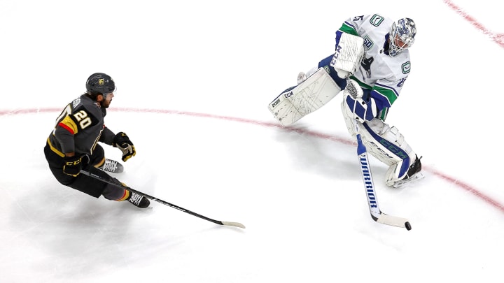 Jacob Markstrom #25 of the Vancouver Canucks clears the puck away from Chandler Stephenson #20 of the Vegas Golden Knights