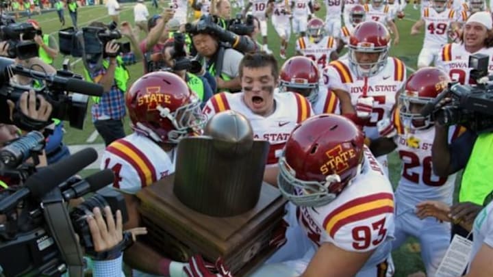 Sep 13, 2014; Iowa City, IA, USA; Iowa State Cyclones Jared Brackens (14), Brandon Jensen (93) and Jevohn Miller (55) grab the Cy-Hawk Trophy after their win against the Iowa Hawkeyes at Kinnick Stadium. The Cyclones beat the Hawkeyes 20-17. Mandatory Credit: Reese Strickland-USA TODAY Sports
