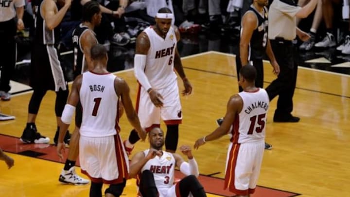 Jun 12, 2014; Miami, FL, USA; Miami Heat guard Dwyane Wade (3) is helped up by teammates Miami Heat forward LeBron James (6), center Chris Bosh (1), and guard Mario Chalmers (15) during the second half of game four of the 2014 NBA Finals against the San Antonio Spurs at American Airlines Arena. Mandatory Credit: Steve Mitchell-USA TODAY Sports
