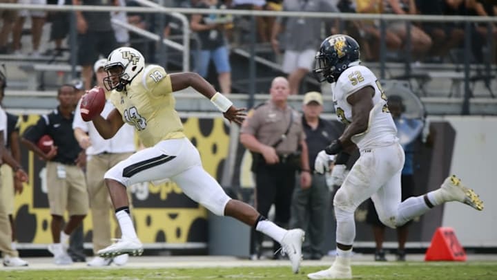 Sep 3, 2015; Orlando, FL, USA; UCF Knights quarterback Justin Holman (13) runs with the ball as FIU Golden Panthers linebacker Treyvon Williams (52) defends during the second quarter at Bright House Networks Stadium. Mandatory Credit: Kim Klement-USA TODAY Sports