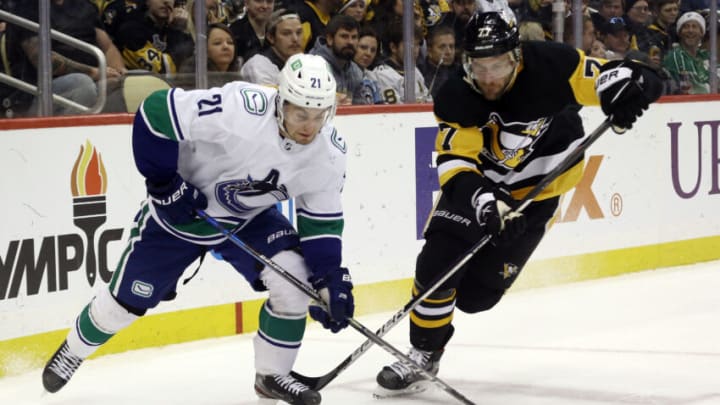 Nov 24, 2021; Pittsburgh, Pennsylvania, USA; Vancouver Canucks left wing Nils Hoglander (21) chases the puck against Pittsburgh Penguins center Jeff Carter (77) during the third period at PPG Paints Arena. The Pens won 4-1. Mandatory Credit: Charles LeClaire-USA TODAY Sports