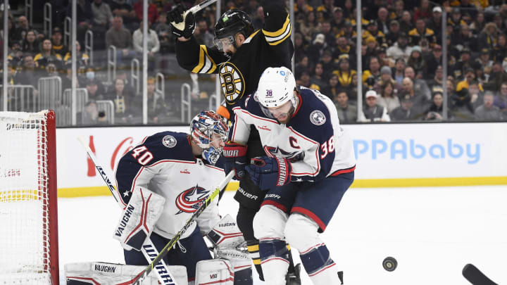 Dec 17, 2022; Boston, Massachusetts, USA; Columbus Blue Jackets center Boone Jenner (38) gets hit by the puck while battling with Boston Bruins left wing Nick Foligno (17) in front of goaltender Daniil Tarasov (40) during the first period at TD Garden. Mandatory Credit: Bob DeChiara-USA TODAY Sports