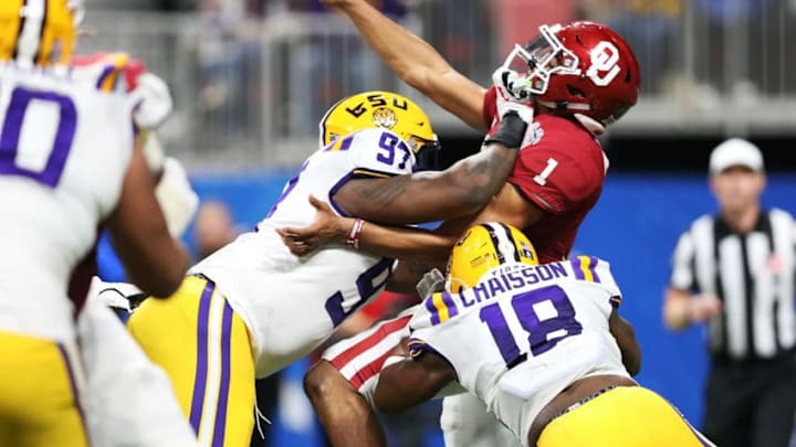 ATLANTA, GEORGIA - DECEMBER 28: Quarterback Jalen Hurts #1 of the Oklahoma Sooners is tackled by defensive end Glen Logan #97 and linebacker K'Lavon Chaisson #18 of the LSU Tigers during the Chick-fil-A Peach Bowl at Mercedes-Benz Stadium on December 28, 2019 in Atlanta, Georgia. (Photo by Carmen Mandato/Getty Images)