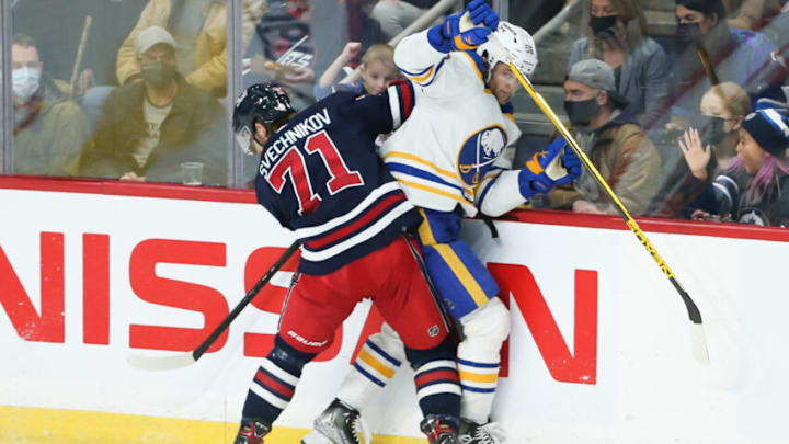 Dec 14, 2021; Winnipeg, Manitoba, CAN; Winnipeg Jets forward Evgeny Svechnikov (71) boards Buffalo Sabres forward Anders Bjork (96) during the third period at Canada Life Centre. Mandatory Credit: Terrence Lee-USA TODAY Sports