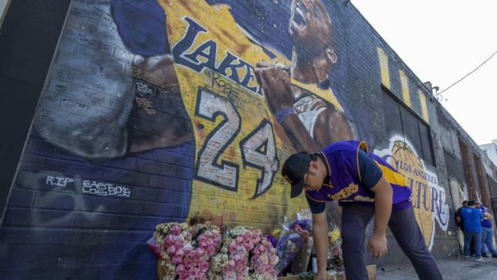 LOS ANGELES, CA - FEBRUARY 24: A man places a candle near a mural for former Los Angeles Lakers basketball star Kobe Bryant during the official memorial ceremony for him and his daughter, Gianna, at nearby Staple Center on February 24, 2020 in Los Angeles, California. Kobe and his 13-year-old daughter were among nine people killed in a helicopter crash on January 26 as they were flying to his Mamba Sports Academy where he was to coach her in a tournament game. (Photo by David McNew/Getty Images)