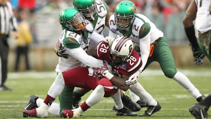 Dec 27, 2014; Shreveport, LA, USA; South Carolina Gamecocks tailback Mike Davis (28) is tackled during the first half as Miami Hurricanes linebacker Denzel Perryman (52) and defensive backs Deon Bush (2) and Antonio Crawford (21) make a tackle in the 2014 Independence Bowl at Independence Stadium. Mandatory Credit: Nelson Chenault-USA TODAY Sports